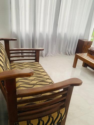 a wooden chair sitting in a room with curtains at Broad view in Ella