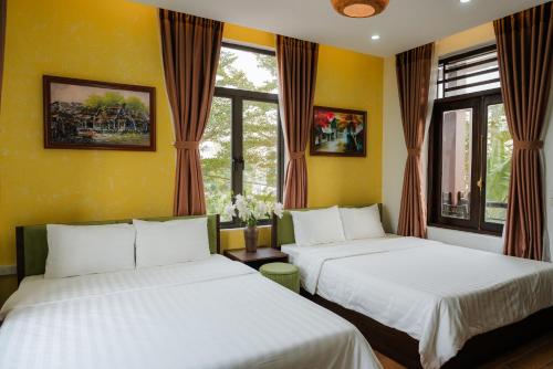 - 2 lits dans une chambre dotée de murs et de fenêtres jaunes dans l'établissement Việt Xưa Homestay, à Ninh Binh
