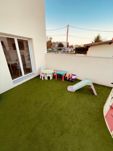 une terrasse avec une pelouse dotée de tables et de chaises. dans l'établissement Maison familiale, à Villenave-dʼOrnon