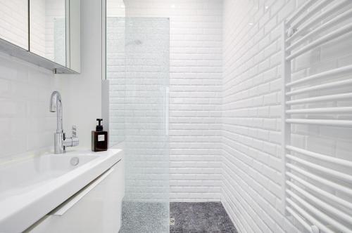 une salle de bain blanche avec une baignoire et un lavabo dans l'établissement Lumineux Place du Commerce, à Paris