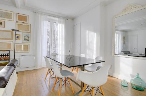 une salle à manger avec une table en verre et des chaises blanches dans l'établissement Lumineux Place du Commerce, à Paris