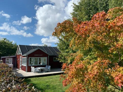 a red house with a porch and a deck at Cozy Red Cottage By Kalø Vig With Seaview in Hornslet