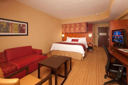 a hotel room with a bed and a couch at Courtyard by Marriott Boston Waltham in Waltham