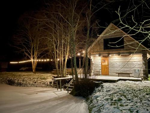 a wooden cabin with a snow covered yard at night at Paluküla Saunad saunahouse in Paluküla