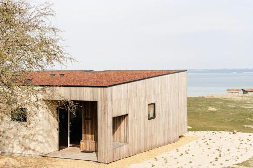 a small house with a red roof on a beach at Enjoy Twosomeness With A View Of Helnæs in Ebberup