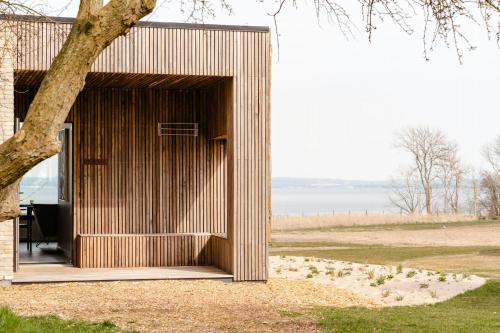 a wooden building with a tree in a field at Enjoy Twosomeness With A View Of Helnæs in Ebberup