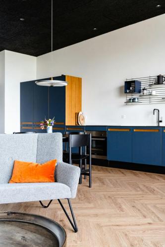 a kitchen with blue cabinets and an orange pillow on a chair at Enjoy Twosomeness With A View Of Helnæs in Ebberup