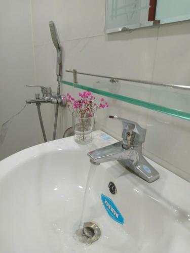 a bathroom sink with a faucet and a vase of flowers at Luna travel in Hanoi