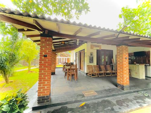 a patio with chairs and tables and a roof at Green Cottage in Anuradhapura