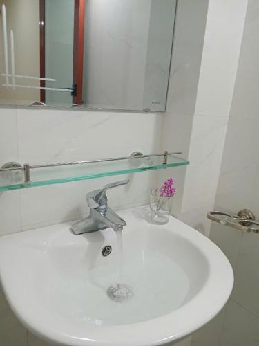a bathroom sink with a mirror and a vase of flowers at Luna travel in Hanoi