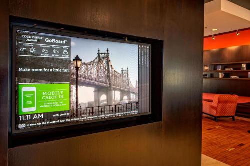 a tv on a wall with a picture of a bridge at Courtyard by Marriott Westbury Long Island in Westbury