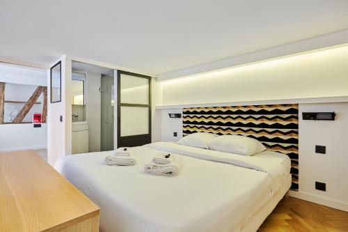 une chambre avec un grand lit blanc avec des serviettes dessus dans l'établissement Duplex Center of Paris by Studioprestige, à Paris