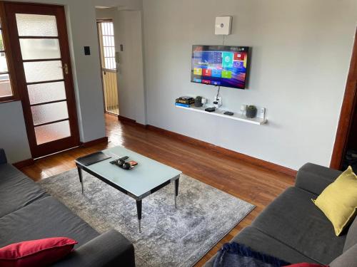 Una sala de estar con un sofá, una mesa y un televisor. en Clarendon Bright Apartment, en Ciudad del Cabo