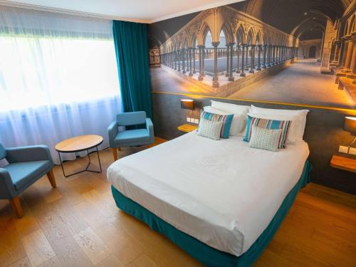 ein Hotelzimmer mit einem großen Bett und Stühlen in der Unterkunft Mercure Mont Saint Michel in Le Mont Saint Michel