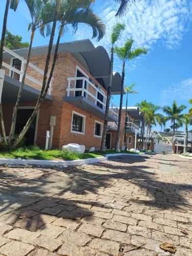 ein Backsteingebäude mit Palmen davor in der Unterkunft Condominio Stoneville in São Sebastião