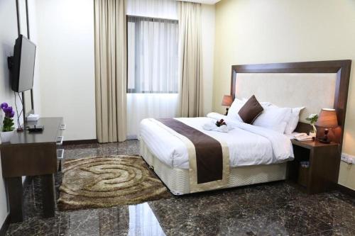 a hotel room with a large bed and a television at Belle Tower Apartments in Manama