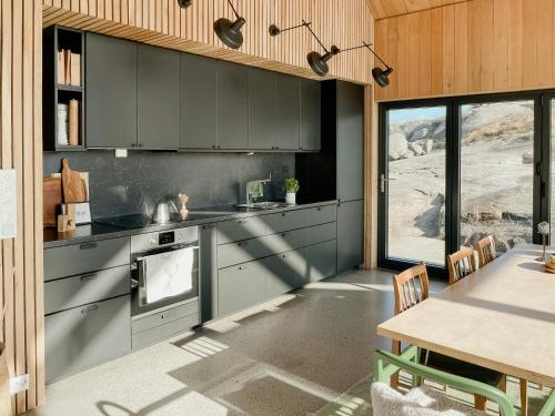a kitchen with gray cabinets and a table with a tableablish at Architect-Designed Gem With Views Of Kistefjellet in Nesvåg