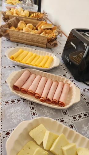 a table topped with plates of food and cheese at Pousada Noa in Cabo Frio