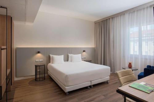 a hotel room with a white bed and a desk at NH Trieste in Trieste