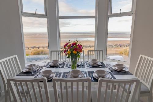 a dining room table with a vase of flowers on it at Sunbeam House 3 Morecambe in Morecambe