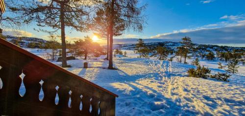 a snow covered hill with the sun in the background at Traditional Cabin By Reinsvatn In Treungen in Treungen
