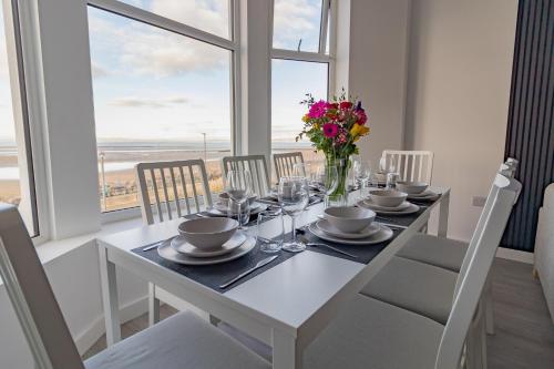a white dining room table with a vase of flowers at Sunbeam House 3 Morecambe in Morecambe