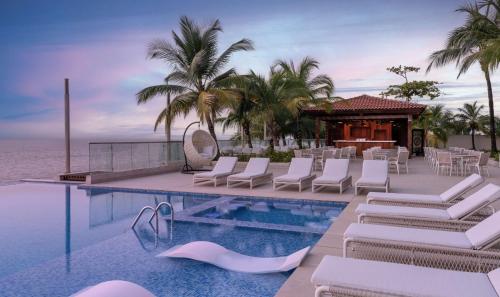 a resort pool with white chairs and a restaurant at Radisson Blu Hotel, Conakry in Conakry