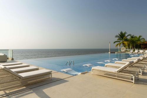 a swimming pool with lounge chairs and the ocean at Radisson Blu Hotel, Conakry in Conakry