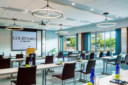 a conference room with tables and chairs and windows at Courtyard Burlington Harbor in Burlington