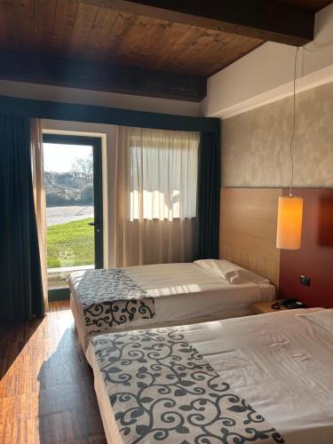 two beds in a hotel room with a window at Cascina Scova Resort in Pavia