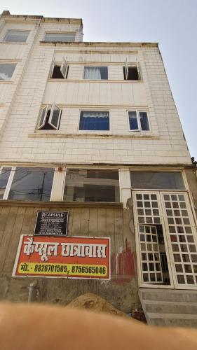 a tall building with a sign in front of it at Capsule Hostel And PG Services in Gorakhpur