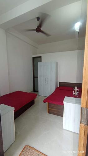 a bedroom with two beds and a red blanket at Capsule Hostel And PG Services in Gorakhpur