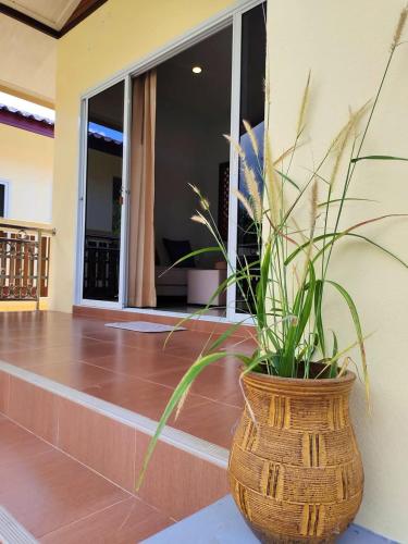 a plant in a wicker vase sitting on a porch at House in Lipa Noi in Ban Na We