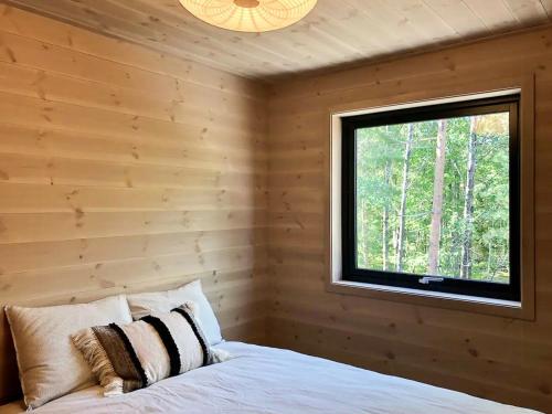 a bedroom with a wooden wall with a bed and a window at Cabin With Panoramic View Of Sandnesfjorden in Risør