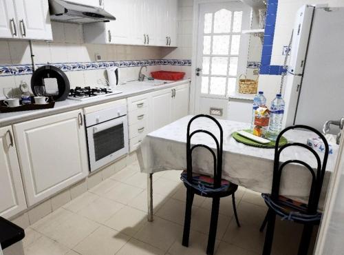 a white kitchen with a table and two chairs at Turquoise view la marsa in El Haouach