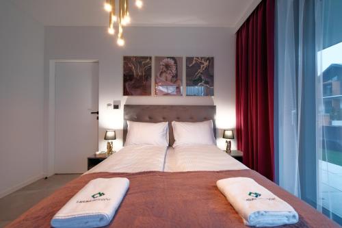 a bedroom with a large bed with two towels on it at Laguna Beskidów Resort - Apartament C18 in Zarzecze