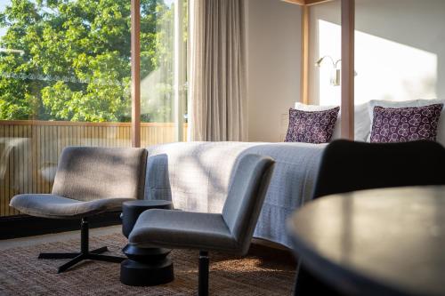 a hotel room with a bed and two chairs and a window at Khiwane Boutique Hotel in Hoedspruit