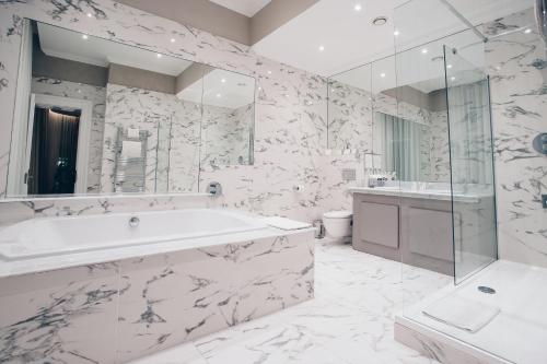 a white bathroom with a tub and a sink at County Hotel & County Aparthotel Newcastle in Newcastle upon Tyne