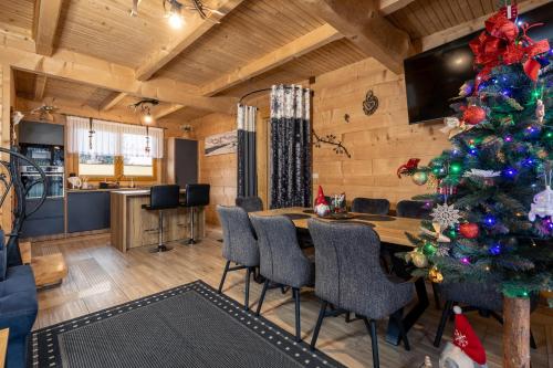 a christmas tree in a living room with a table and chairs at Leśny Dwór Premium Chalets Zakopane in Murzasichle