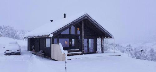 a snow covered cabin with a car parked next to it at Cozy Family Cabin In Uniquely Situated Hiking Area in Indre Standal
