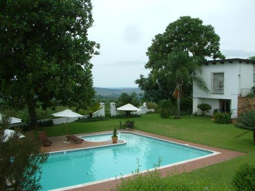 a swimming pool in a yard next to a house at Plumbago Guest House in Hazyview