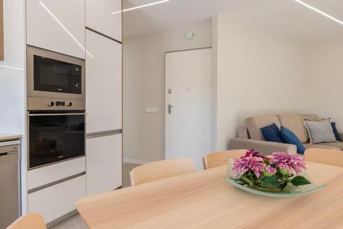 a kitchen with a table with a bowl of flowers on it at Apartamento novo junto ao metro - 1D in Lisbon