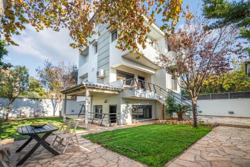 an exterior view of a white building with a yard at Indoor pool villa, near the beach, Lagonisi in Kalívia Thorikoú