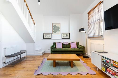 a living room with a green couch and a table at Stylish Chelsea Flat with Luxe Comfort & Charm in London
