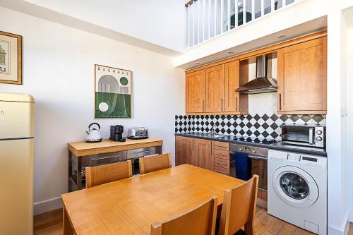 a kitchen with a wooden table and a dining room at Stylish Chelsea Flat with Luxe Comfort & Charm in London
