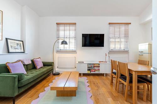 a living room with a green couch and a table at Stylish Chelsea Flat with Luxe Comfort & Charm in London