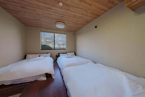 two beds in a room with a window at akesuke in Minamiawaji