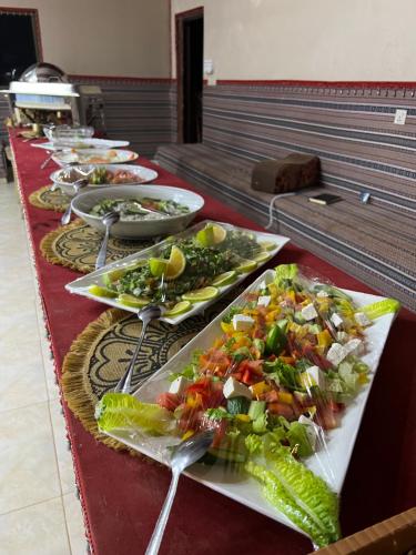 a buffet with plates of food on a red table at Radisson Wadi Rum Camp in Wadi Rum