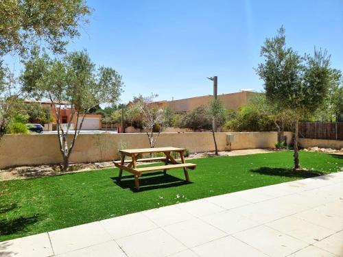 a wooden bench sitting on top of green grass at A villa in the desert in Midreshet Ben Gurion