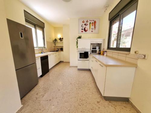 a large kitchen with white cabinets and appliances at A villa in the desert in Midreshet Ben Gurion